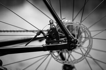 Fototapeta premium Close-up of a bicycle wheel showcasing metallic spokes and hub against a blurred green background, emphasizing craftsmanship and outdoor activity. Ideal for cycling, transportation, and fitness themes