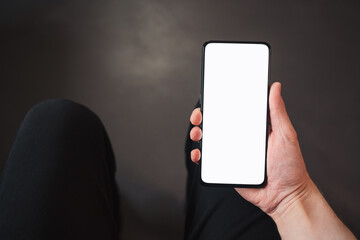 pov shot of man hand hold phone with white screen in dark interior