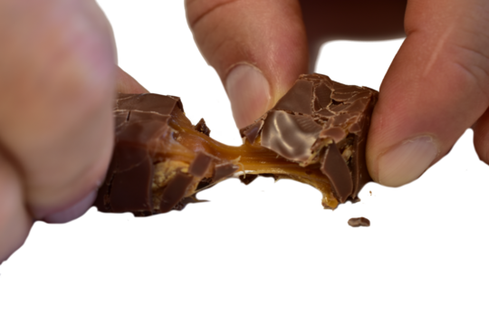 Men's hands tear apart a candy with sticky caramel.