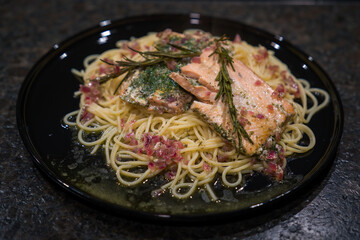 fresh cooking at home and ready to eat - rosted salmon with herbs, olive oil and red onions on spaghetti      