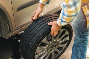 Man replacing a tire on a vehicle in a residential area during daylight hours