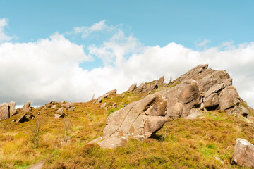 Rocky landscape under a clear blue sky with fluffy clouds in the background