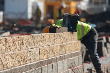 Construction worker mason lays bricks in sunny outdoor setting at a construction site