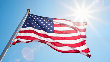 Obraz premium American flag waving in bright sunlight against blue sky