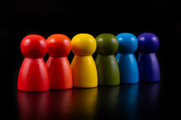 Multi-colored symbolic figures of wooden people on a black background