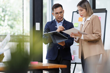 Asian businessman and businesswoman looking at laptop computer in the workplace office, Feeling happiness
