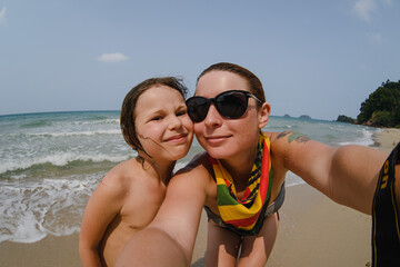 Fototapeta premium Selfie mom and daughter portraits in Asia in Thailand on the background of the ocean