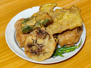 Gorengan, a traditional Indonesian street food consisting of tahu brontak, fried banana, bakwan, tempe mendoan, etc. Served with green chili.