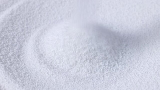 White natural organic sweet Sorbitol sweetener granules falling down close up. Sugar substitute concept