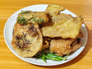 Gorengan, a traditional Indonesian street food consisting of tahu brontak, fried banana, bakwan, tempe mendoan, etc. Served with green chili.
