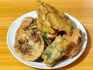 Gorengan, a traditional Indonesian street food consisting of tahu brontak, fried banana, bakwan, tempe mendoan, etc. Served with green chili.