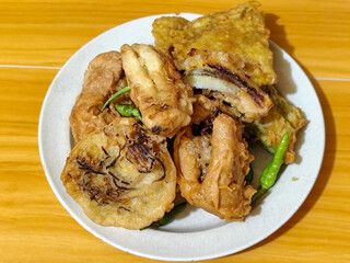 Gorengan, a traditional Indonesian street food consisting of tahu brontak, fried banana, bakwan, tempe mendoan, etc. Served with green chili.