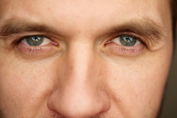 Intense gaze with gray eyes. Male face with focused expression. Close up of human eyes looking...