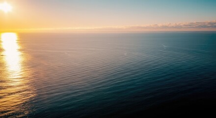 Obraz premium Tranquil ocean at sunrise with clear sky and gentle waves
