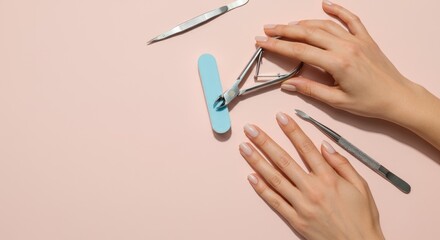 Close-up on manicured hands and nail tools light surface