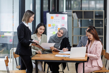 Happy asian business woman executive ceo leader discussing project management planning strategy working with diverse colleagues company team at office corporate board group meeting.
