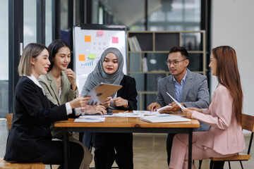 Asian female ceo and multicultural business people discussing company presentation at boardroom table. Diverse corporate team working together in modern meeting room office.