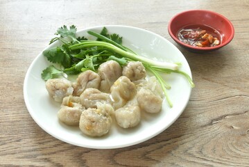 steamed fish dumpling with parsley and spring onion on plate dipping spicy sour sauce 