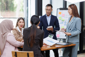 Asian female ceo and multicultural business people discussing company presentation at boardroom table. Diverse corporate team working together in modern meeting room office.