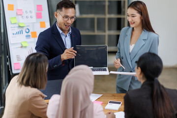Asian female ceo and multicultural business people discussing company presentation at boardroom table. Diverse corporate team working together in modern meeting room office.