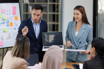 Asian female ceo and multicultural business people discussing company presentation at boardroom table. Diverse corporate team working together in modern meeting room office.