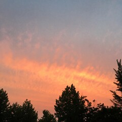 Obraz premium 노을진 하늘과 산들구름, 나무가 어우러진 자연풍경을 담은 사진