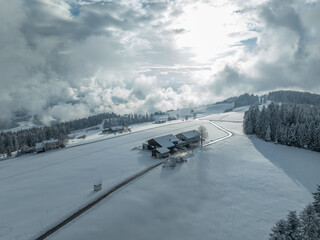 aerial photo of a snowy landscape with forest and farm houses in the Bregenz Forest in Vorarlberg,...
