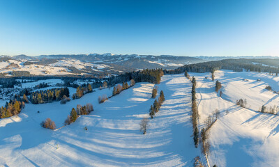 Aerial photo of snowy landscape in moody sunset twilight in the Allgaeu mountains next to Oberreute in Bavaria, Germany 