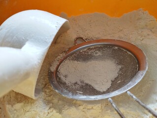 Sieve and scoop in a bowl with white wheat flour. sifting wheat flour.