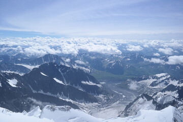 A stunning rock formation covered in snow, set against a clear blue sky with fluffy clouds in the...
