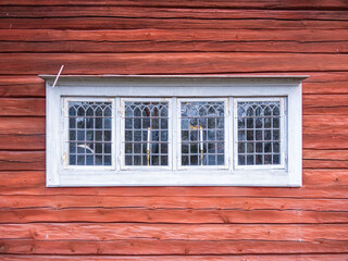A rustic wooden wall with a vintage white-framed window