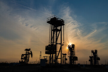 A silhouette of a pumping unit working in the evening