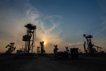 A silhouette of a pumping unit working in the evening