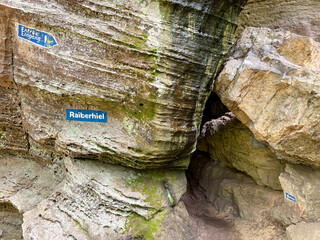Cave entrance between rocks in the forest in the Mullerthal region, Luxembourg.