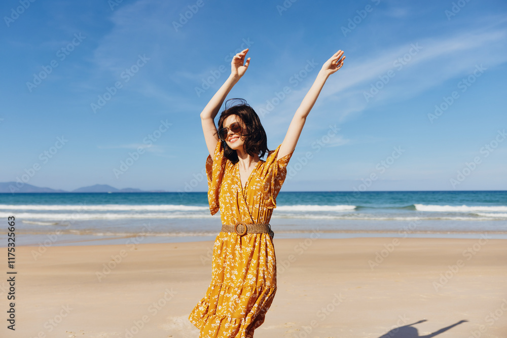 Sticker Woman in a flowing yellow dress standing on sandy beach with arms outstretched on a sunny day