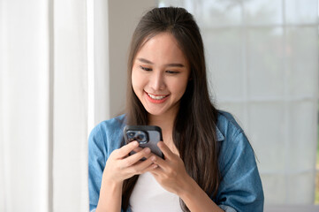 Young Asian woman enjoy using smartphone at home