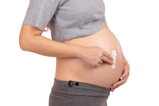 Pregnant woman applying cream to her belly for skincare and stretch mark prevention