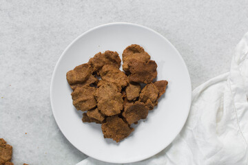 Overhead view of kuli-kuli on a white plate, top view of nigerian groundnut cakes on a plate, fresh homemade nigerian kulikuli on a ceramic plate