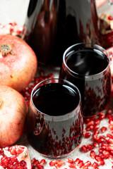 Pomegranate juice in jug and glasses among pomegranates