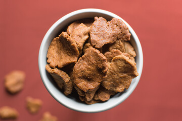 Overhead view of kuli-kuli in a white bowl, top view of nigerian groundnut cakes in a bowl, fresh homemade nigerian kulikuli in a ceramic bowl