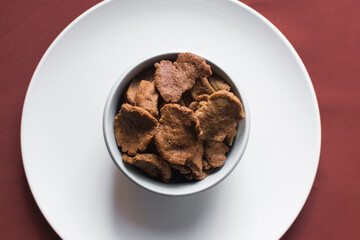Overhead view of kuli-kuli in a white bowl, top view of nigerian groundnut cakes in a bowl, fresh homemade nigerian kulikuli in a ceramic bowl