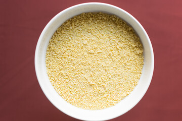 Yellow garri in a white bowl, top view of nigerian garri in a ceramic bowl, fried cassava, garri for eba
