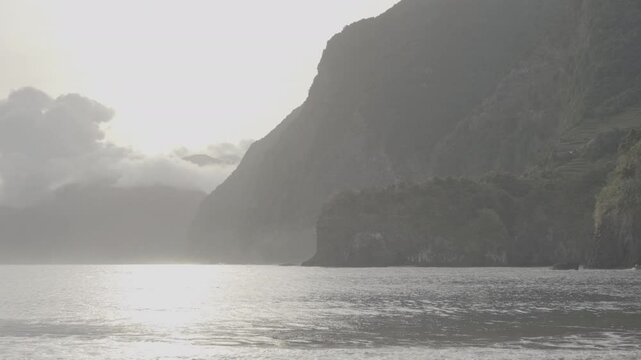 Golden sunset over tropical beach with waves lapping against shore and dramatic cliffs in background (SLOG3)