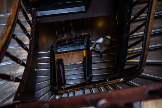 Old wooden stairs in a circle. Old house in the woods. Top down view. A person is going down the stairs