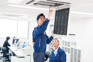 ビルのエアコンの点検をする作業服の男性