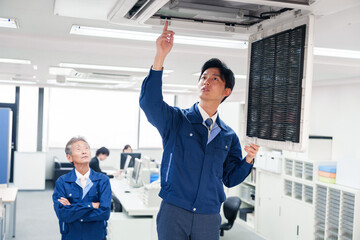 ビルのエアコンの点検をする作業服の男性