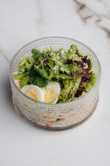Fresh edamame, lettuce, spinach, and boiled egg salad sprinkled with grated cheese, served in a glass bowl, offering a nutritious and vibrant meal. Restaurant or cafe menu, cookbook recipe