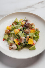 Vibrant salad featuring grilled chicken, mango, avocado, walnuts, and lettuce topped with grated parmesan cheese, served on plate for a fresh and healthy meal. Restaurant or cafe menu, cookbook recipe