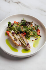 Slices of grilled chicken breast stuffed with pesto, paired with a fresh salad of tomatoes and arugula, elegantly arranged on a white plate. Restaurant or cafe menu, cookbook recipe
