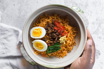 Overhead view of Spicy instant noodles in a claypot, top view of spicy ramen noodles with soft boiled egg in a donabe